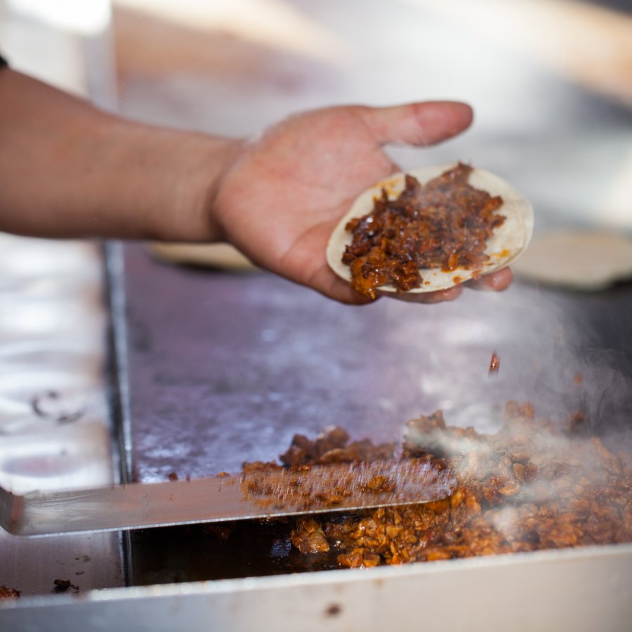 Cook filling a fresh tortilla straight off the plancha.